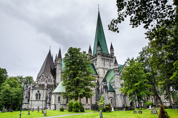 Nidaros cathedral in Trondheim, Norway, with green trees and garden in the foreground