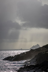 a view of the wild atlantic way off the coast of the ring of kerry in ireland showing skellig michael and surrounding islands in beautiful strong light with cloudy skies 