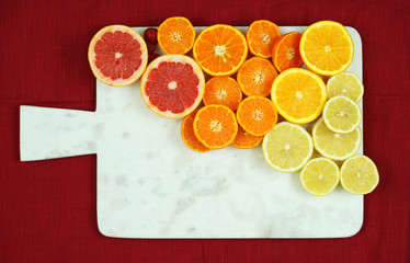 Colorful fruit platter assembly with citrus fruit on white marble board with copy space.