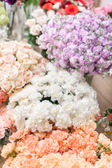 Floral carpet, flower texture, shop concept. Beautiful fresh blossoming flowers roses, spray roses, lilac gillyflower and carnation. Blossom of pastel color in vases and pails. Top view.