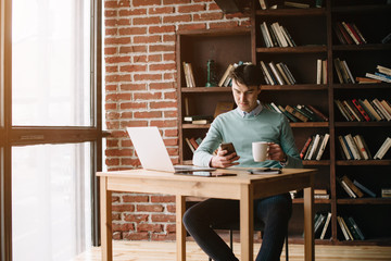 Young man drawing template for the web site associated with digital marketing, current trends and tendencies of UX / UI design. Businessman who rules his company remotely, like a freelancer