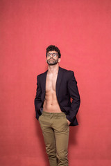 Obraz premium one young confident handsome man, posing shirtless, wearing a suit and pants.