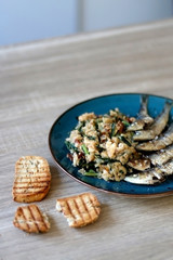 Grilled sardines and salad made with chicory, white beans and dried tomatoes. Selective focus.