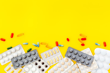 Medicine help with drugs on work desk of doctor yellow background top view mock up