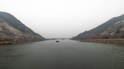 The walk way along the river and the bridge with the Chinese style at the Longmen Grottoes.