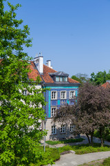 Early color houses surrounded by green trees. Warsaw