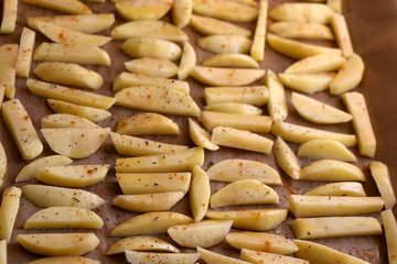 Potato slices seasoned with olive oil, chili and basil, before baking. Healthier alternative to fries. Top view.