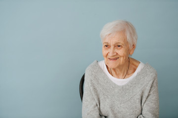 Portrait of elderely grey haired woman in a comfortable sweater at home