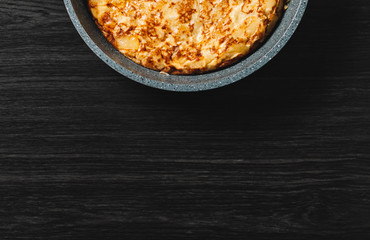 tortilla de patatas on dark wood background, typical spanish dish. Copy space for text and top view