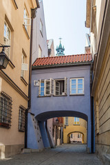 Narrow street with an arch and old lanterns. Warsaw.