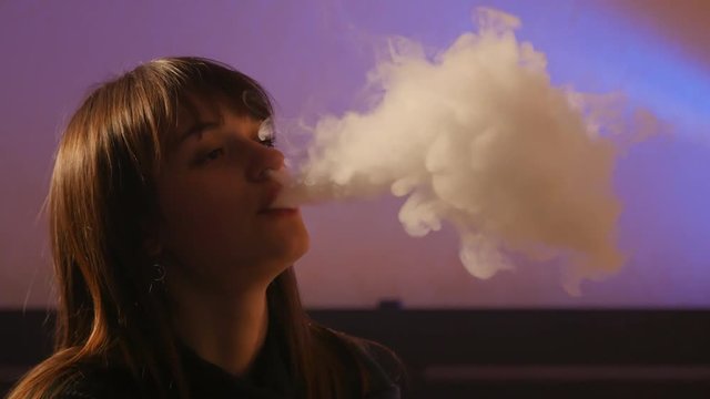 portrait of vaping pretty woman at home at night