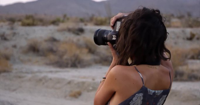 stylish female photographer taking photos out in middle of the desert