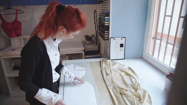 Dressmaker measuring textile using pattern in atelier. 4K