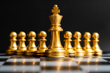 Gold king chess piece stand in front of pawn on black background (Concept of leadership, management)