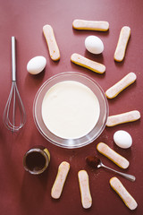 Preparing a tasty tiramisu , step by step visual guide, ingredients ngredients for making perfect Italian dessert. are displayed on a brown board, top view.