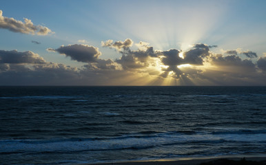 Sunrise on a Florida beach with rays behind the clouds.