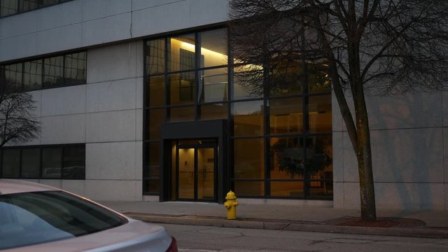 Establishing shot of entrance to generic corporate building in metropolitan area in evening
