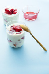 Tiramisu with strawberry  in glass on a blue board, natural backlight