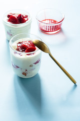 Tiramisu with strawberry  in glass on a blue board, natural backlight