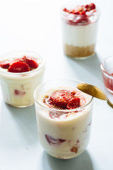 Tiramisu with strawberry  in glass on a blue board, natural backlight