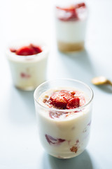 Tiramisu with strawberry  in glass on a blue board, natural backlight