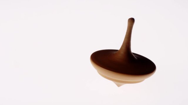 Closeup Slow Motion Shot Of A Vintage Wooden Spin Top Wobbling And Coming To Halt On White Background