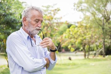 Portrait of stressful sad senior caucasian old man in the park outdoors with copy space. Spring...