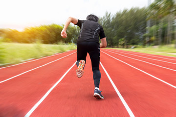 Obraz premium portrait of young male athlete running on running track (back view)
