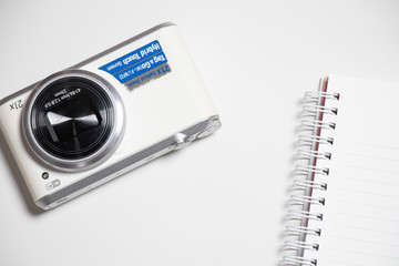 camera with blank spiral notebook on Flat lay