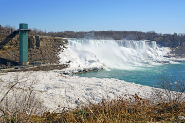 View of the American Falls in Niagara Falls in winter with frozen ice and snow in the Niagara River