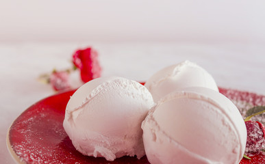 Vanilla ice cream lies on a red plate. Decorated with a red rose. Homemade organic product. Selective focus, side view.