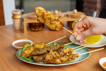 Woman hand holds a Pieces of satay (chicken, beef, pork)