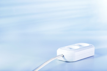 Electric socket for connecting electrical equipment on light blue surface with copy space. Concept supply or consumption energy.