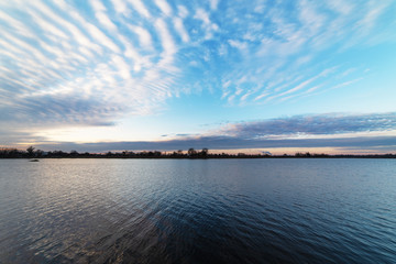 Beautiful evening sky with multicolored clouds over the quiet waters of Svityaz Lake.