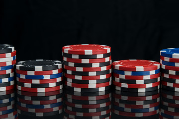 multi-colored chips, for playing in a casino, stand by numerous pyramids, on a black reflecting table, there is an inscription above