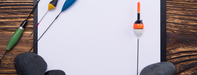 background for recording, the white sheet on the tablet lies on a wooden antique surface, with a set of items for sport fishing, floats