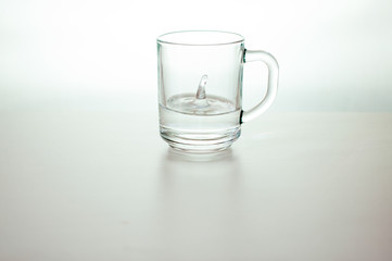 Water drop in transparent glass on gray background. purified fresh drink water on table