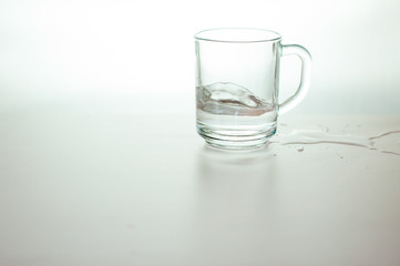 Water wave in transparent glass and puddle on gray background. purified fresh drink water on table