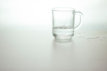 Water wave in transparent glass and puddle on gray background. purified fresh drink water on table