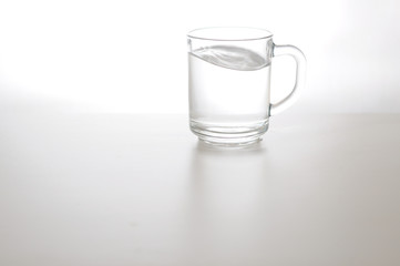 Water wave in transparent glass and puddle on gray background. purified fresh drink water on table