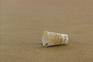 close up of a clear plastic cup on clean beach sand