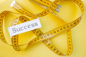 yellow measuring tap ,diet, dream to be slim, healthy concept, results of fitness jogging and sticking to healthy lifestyle.success. measuring tape and word success - conceptual.dream of a beautiful