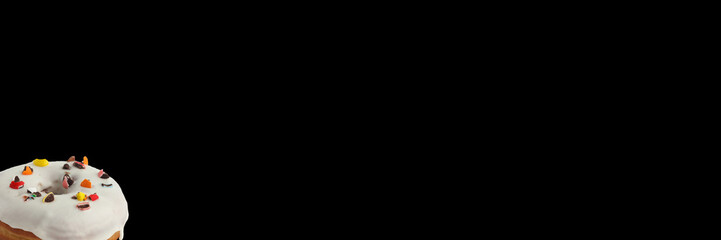 Appetizing donut in white glaze with a decoration on a black background. Isolated. Banner.