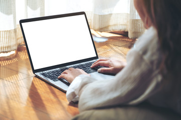 Fototapeta premium Mockup image of a woman typing on laptop computer with blank white desktop screen while laying down on the floor with feeling relaxed