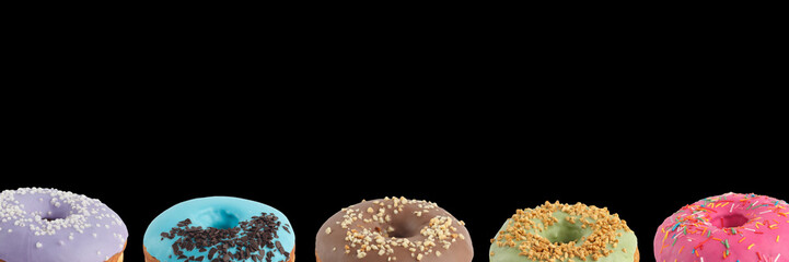 Appetizing donuts with multi-colored icing on a black background. Isolated. Banner.