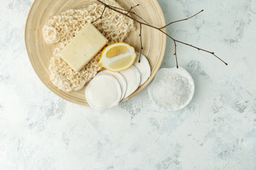 Top view of organic spa skincare bodycare products - lemon, sea salt, soap, zero waste sponge, massage gloves on wooden plate - minimal stylish spa wellness background