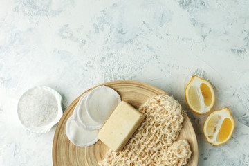 Top view of organic spa skincare bodycare products - lemon, sea salt, soap, zero waste sponge, massage gloves on wooden plate - minimal stylish spa wellness background