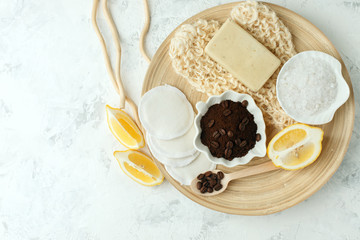 Ingredients for prepare homemade coffee scrub. Coffee grains, sea salt, soap, lemon on wooden plate and gray background, wellness homemade stylish organic concept