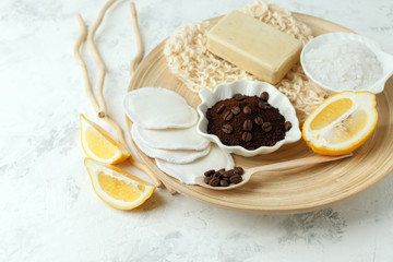 Set for anti-cellulite massage procedures. Coffee scrub, coffee grains, lemon, soap, sponge on wooden plate and gray background, wellness homemade organic concept