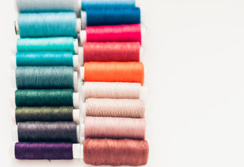 Colored sewing thread coils on white background with copy space for text.
